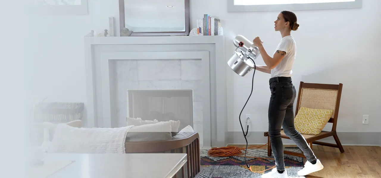 A woman fogging a living room with a Superstratum Whole Home Detox deodor bomb