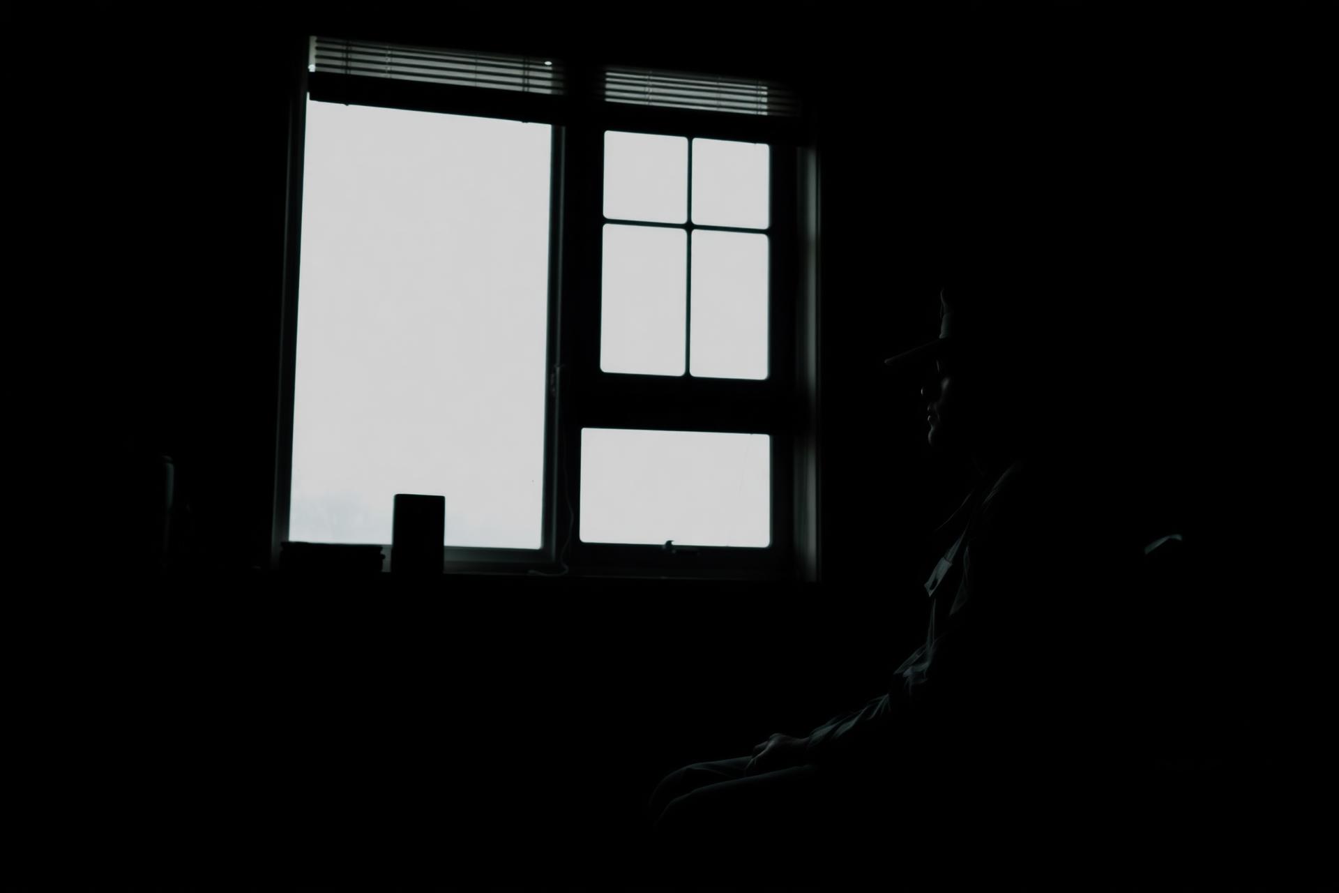 Service member silhouetted at a window in a dim room